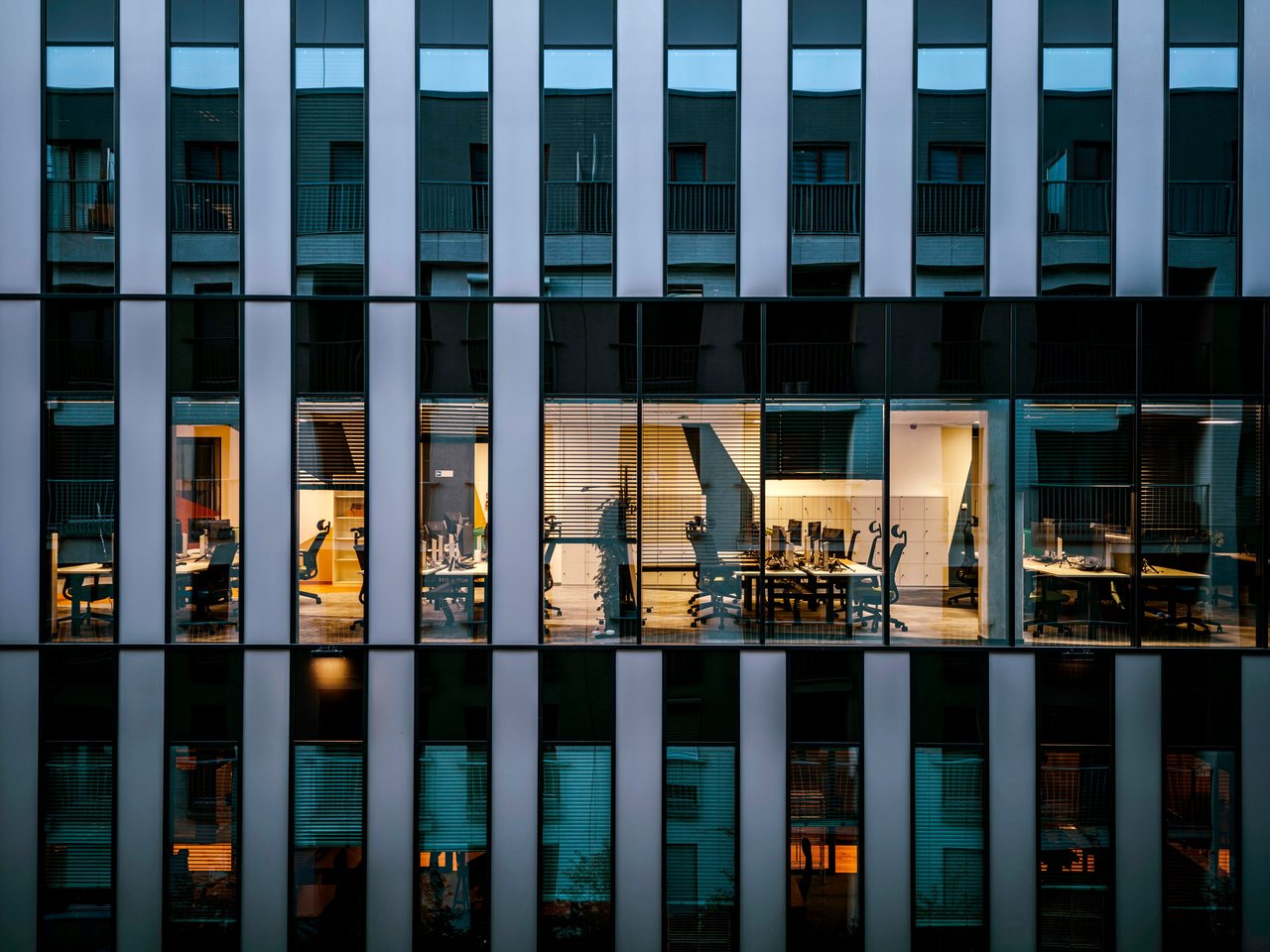 Lit office windows across a city building at dusk