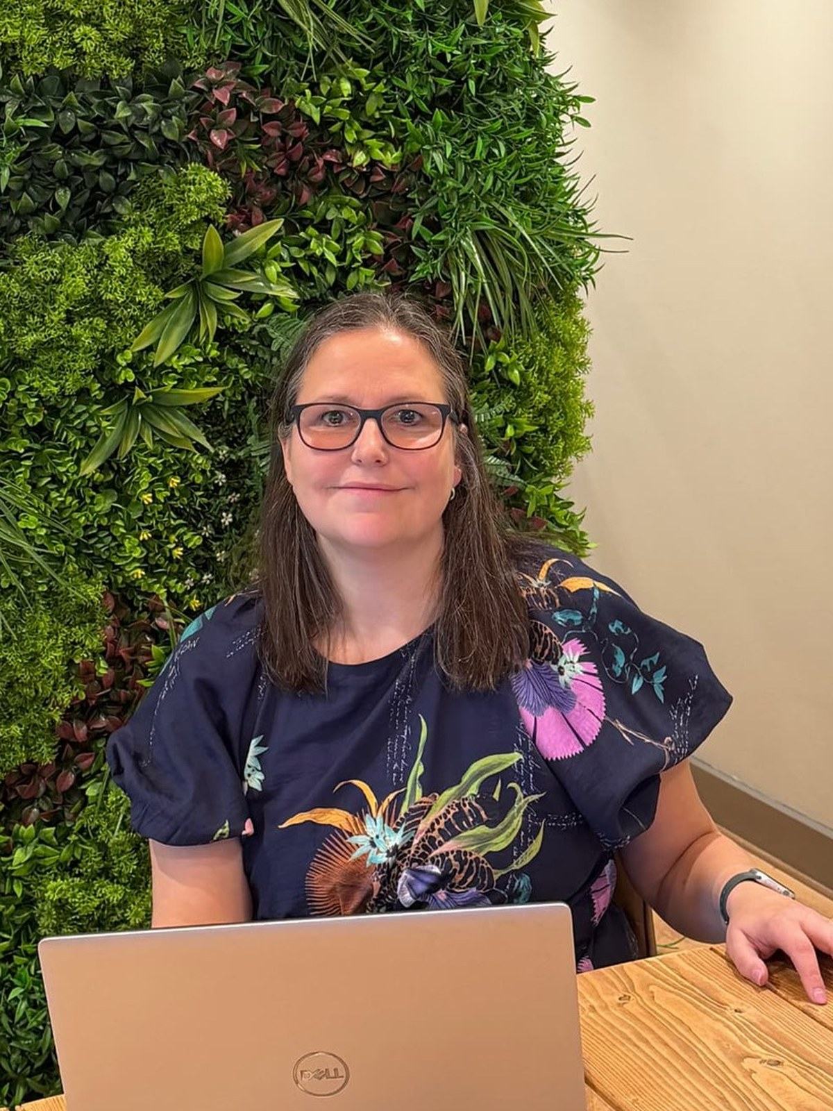 Amanda Weekes working at a laptop in front of a living green wall