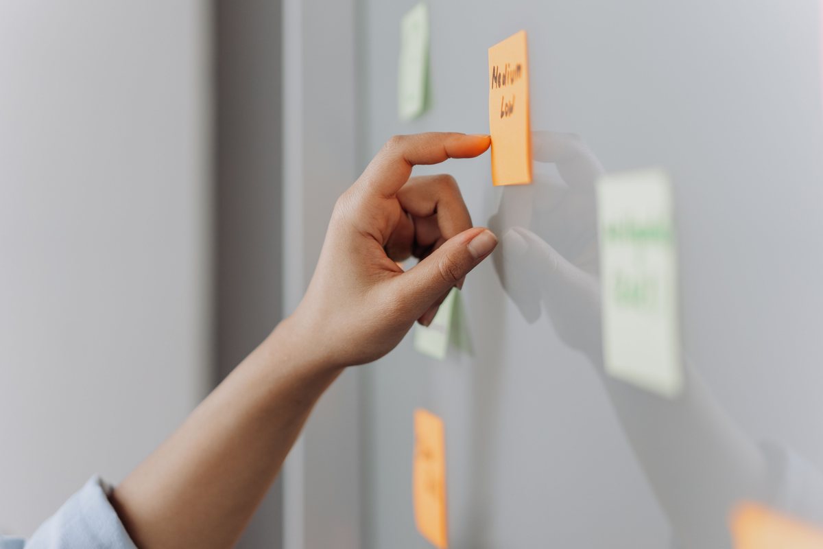 A hand placing a note on a planning wall